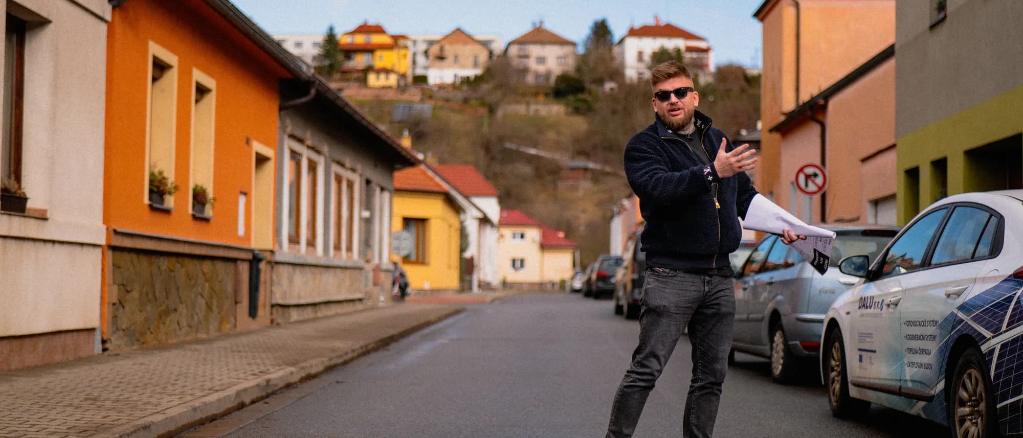 Maxim Ponomarenko s plánem nemovitosti v ruce na ulici rodinných domů