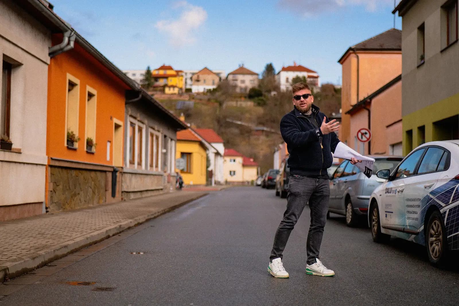 Maxim Ponomarenko v ulici řadových domů s podklady k nemovitosti v ruce