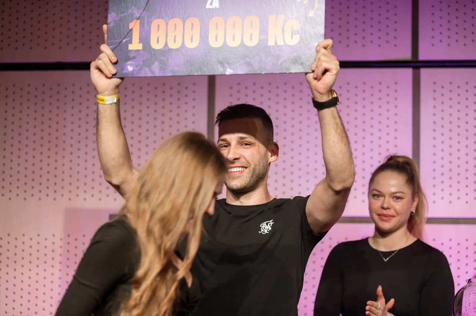 Výherce zvedá nad hlavu šek na 1 000 000 Kč
