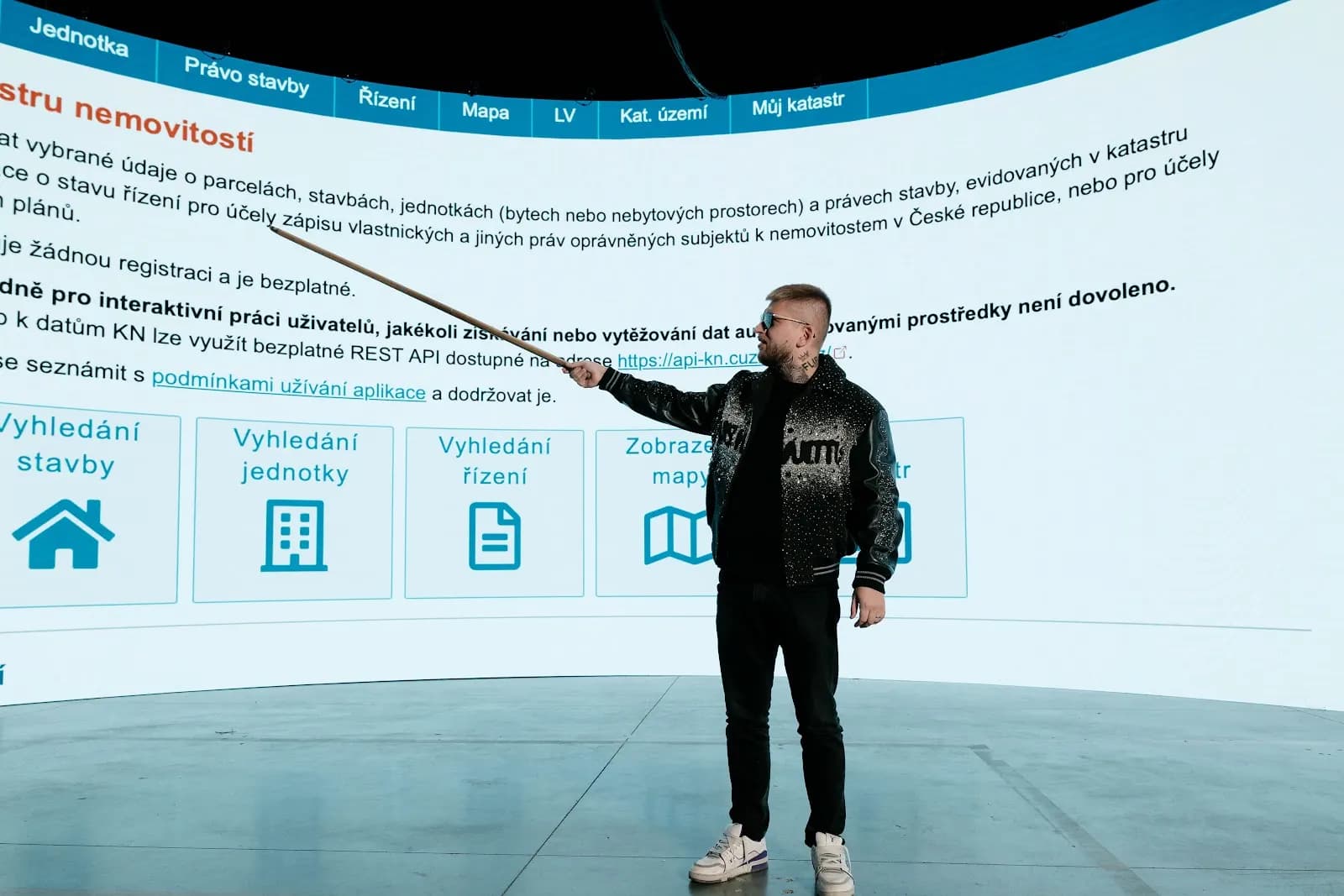 Maxim Ponomarenko ukazuje na nahlížení do katastru nemovitostí promítnuté na velké obrazovce