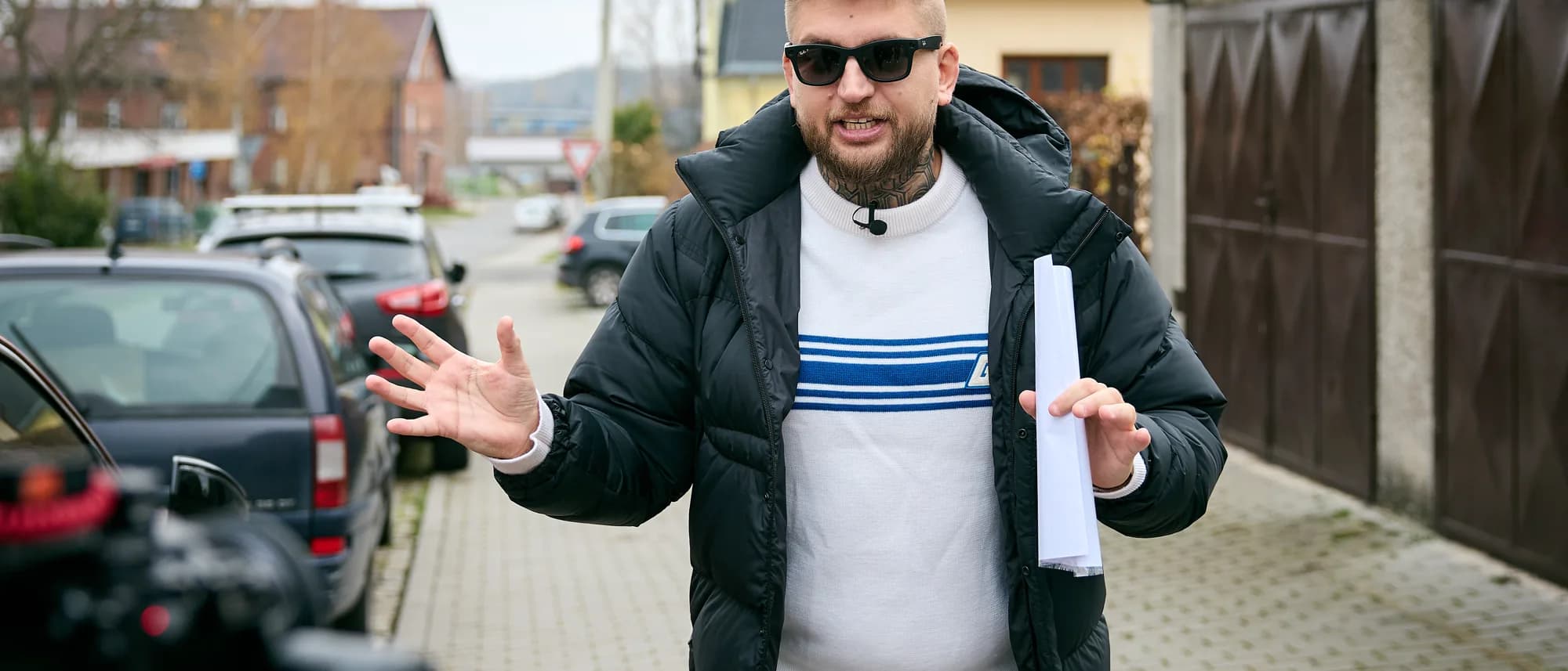 Maxim Ponomarenko s plánem nemovitosti v ruce v ulici rodinných domů